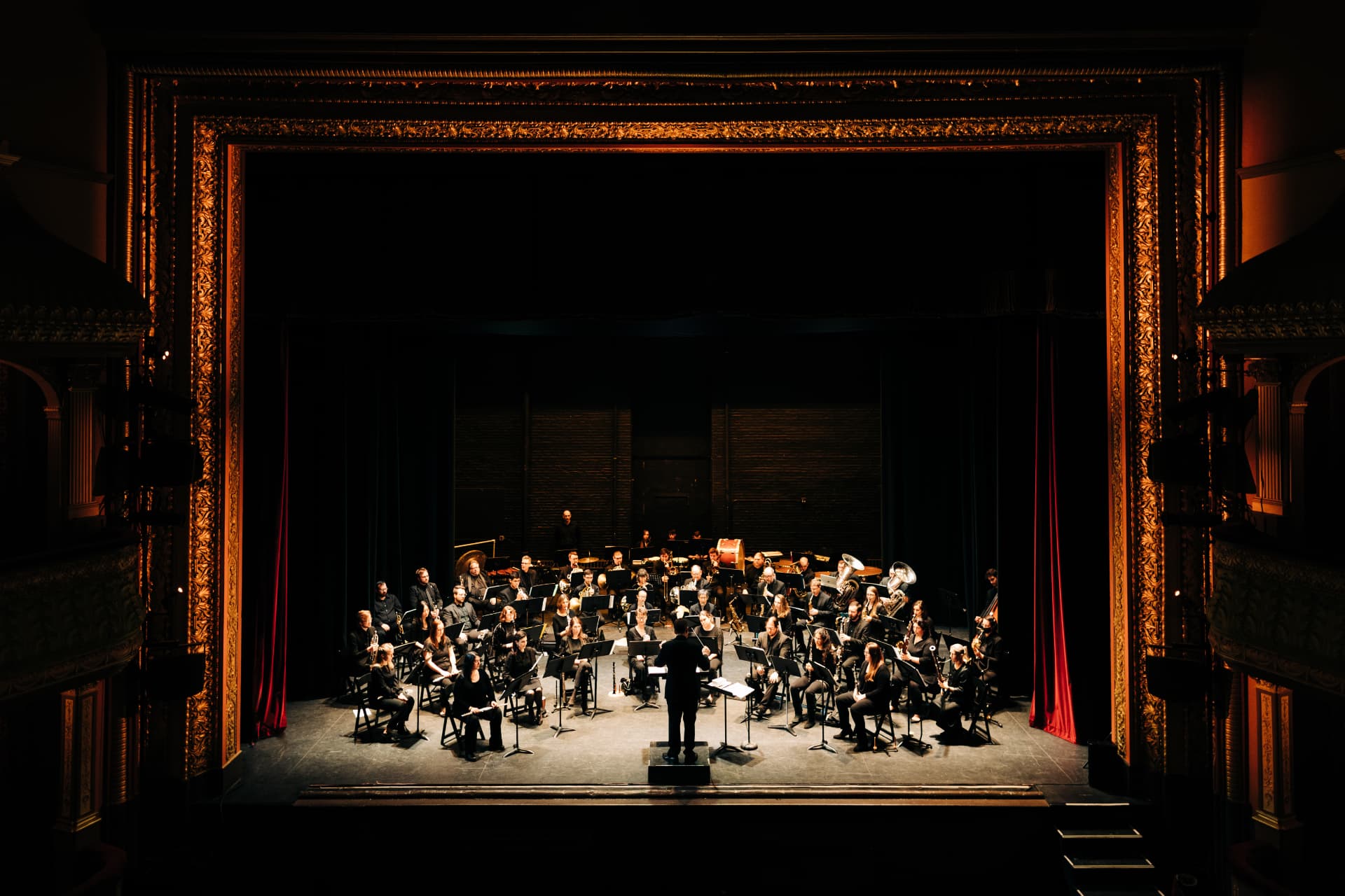The Valley Winds wind ensemble performing on a theater stage under warm lights
